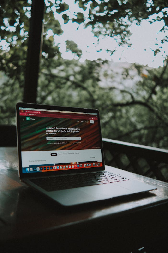 Mastering the First Impression: Your intriguing post title goes here Open laptop showing a website screen on a wooden table in an outdoor terrace setting.